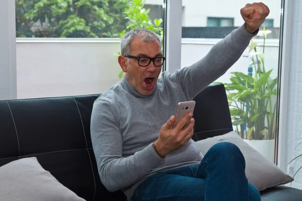 Heyecanlı adam zaferi ve cep telefonuyla kutluyor.