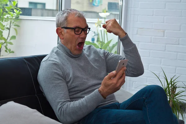 Heyecanlı adam zaferi ve cep telefonuyla kutluyor.