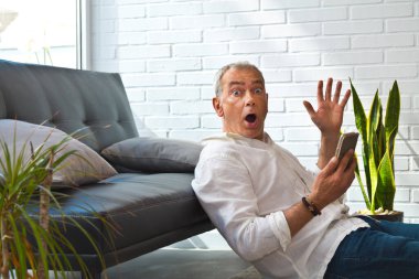 mature man with phone and surprise gesture