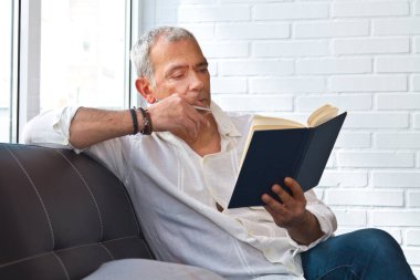 relaxed man reading a book on the armchair