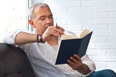 relaxed man reading a book on the armchair