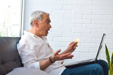 surprised middle-aged man with laptop and credit card