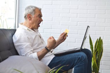 happy middle-aged man with laptop and credit card