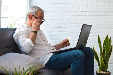 Bilgisayarı ve kredi kartı olan orta yaşlı bir adam.