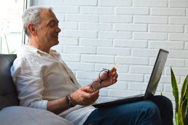 Bilgisayarı ve kredi kartı olan orta yaşlı bir adam.