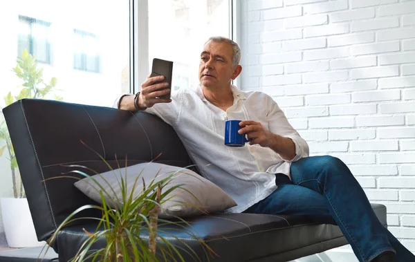 Задоволений Чоловік Розслабляється Своїй Вітальні Використовуючи Мобільний Телефон Маючи Каву — стокове фото