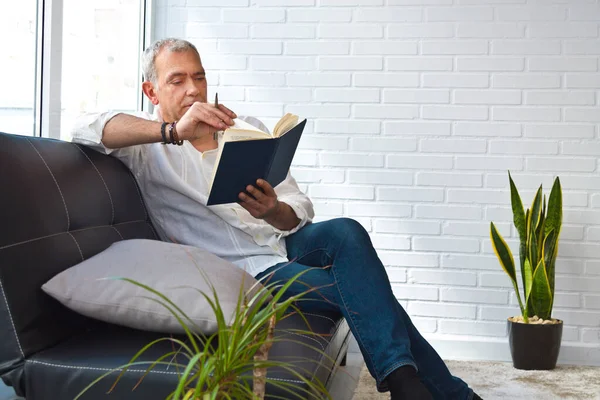 relaxed man reading a book on the armchair