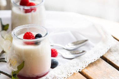 Cam kavanozlarda ahududu ve yaban mersini bulunan Yunan yoğurdu