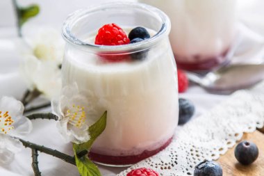 Cam kavanozlarda ahududu ve yaban mersini bulunan Yunan yoğurdu