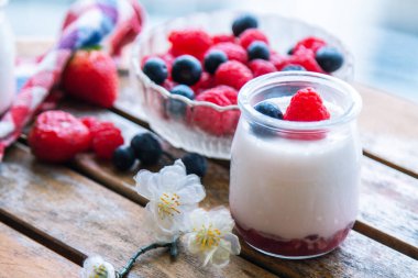 ahududulu yoğurt ve ahşap arka planda yaban mersini.