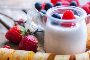 ahududulu yoğurt ve ahşap arka planda bant, diyet ve yiyecek konseptiyle yaban mersini.