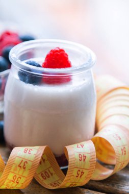 ahududulu yoğurt ve ahşap arka planda bant, diyet ve yiyecek konseptiyle yaban mersini.