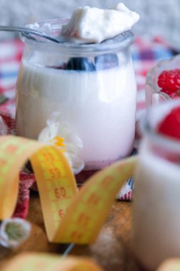 ahududulu yoğurt ve ahşap arka planda bant, diyet ve yiyecek konseptiyle yaban mersini.