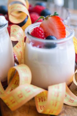 ahududulu yoğurt ve ahşap arka planda bant, diyet ve yiyecek konseptiyle yaban mersini.