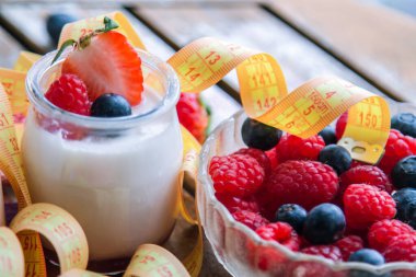 ahududulu yoğurt ve ahşap arka planda bant, diyet ve yiyecek konseptiyle yaban mersini.