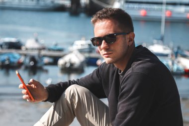 Marinadaki genç adam cep telefonunu kullanıyor.