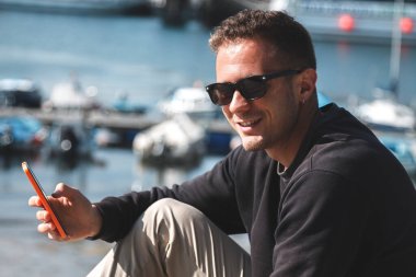 Marinadaki genç adam cep telefonunu kullanıyor.