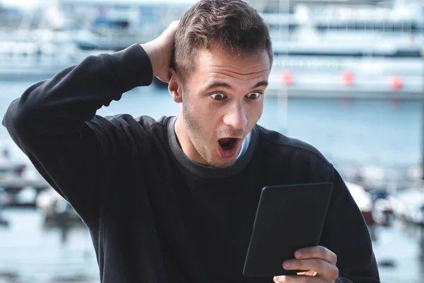 Mann Mit Überraschtem Gesichtsausdruck Blickt Auf Digitales Tablet Seehafen Reisekonzept — Stockfoto