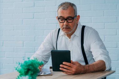 Evinde ya da ofisinde tableti olan hippi bir adam.