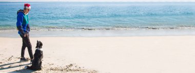 Kumsalda köpekli bir adam Noel 'i kutluyor