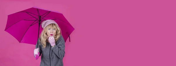 woman with cold and with umbrella on pink background