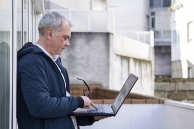 Sokakta dizüstü bilgisayar kullanan adam.