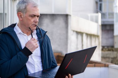 Sokakta dizüstü bilgisayar kullanan adam.