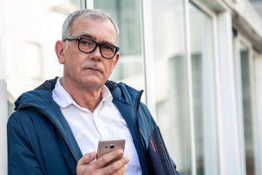 Cep telefonu ve dizüstü bilgisayarı olan olgun bir adam