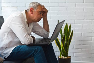 Ofisinde ya da iş yerinde bilgisayarından rahatsız ve bunalmış bir adam.