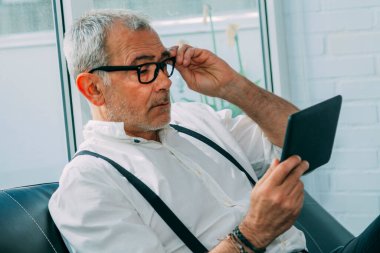 Ofiste veya işyerinde dijital tablet kullanan gözlüklü iş adamı