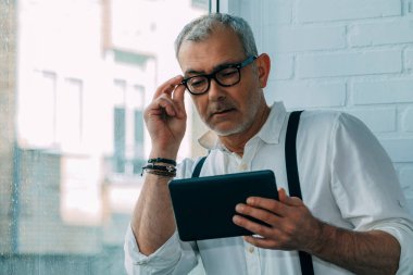 Ofiste veya işyerinde dijital tablet kullanan modern hipster adam