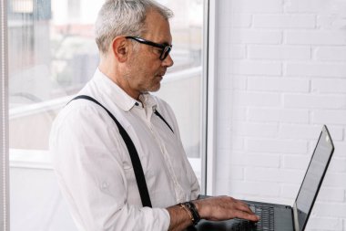 Bilgisayarı ofiste ya da evde olan olgun bir adam.