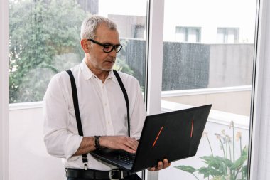 Bilgisayarı ofiste ya da evde olan olgun bir adam.