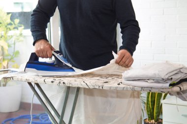 İnsan evde demirle ütü yapıyor, ev işlerinde eşitlik kavramı.