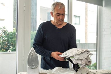 İnsan evde demirle ütü yapıyor, ev işlerinde eşitlik kavramı.