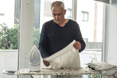 Evde ütüleyen olgun bir adam.