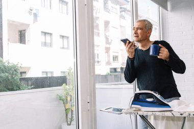 Olgun erkek gömlek evde ütü yaparken cep telefonunuzun konuşma