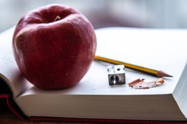 Kitaplar, kalemtıraş, masada kalem ve elma, okula dönüş konsepti.