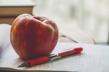Okul konseptine dönelim. Masada elma olan bir kitap.