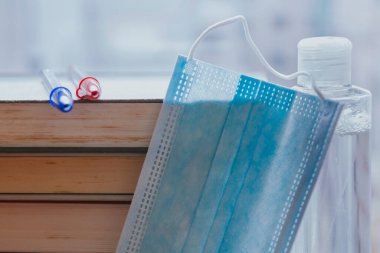 Kitaplar, kalemler, tıbbi maske ve masadaki hidrokolik jel, okula geri dönüş konsepti