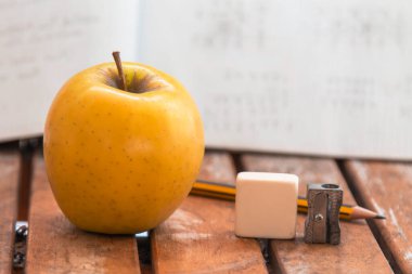 Kitaplar, kalemtıraş, masada kalem ve elma, okula dönüş konsepti.