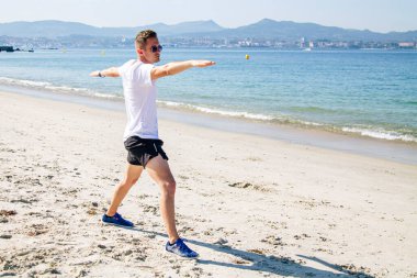 Genç adam plajda spor yapıyor. Rahatlamak için.