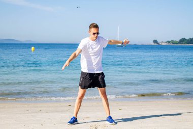 Genç adam plajda spor yapıyor. Rahatlamak için.