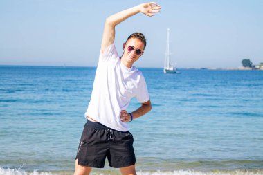 Genç adam plajda spor yapıyor.