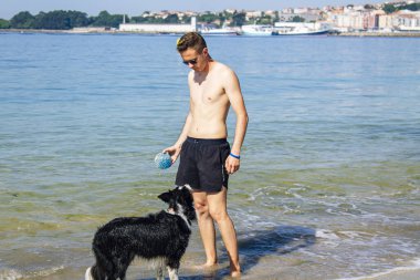 Sahilde evcil hayvanıyla oynayan bir adam.