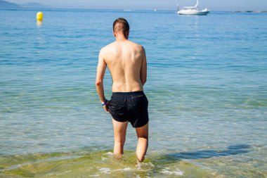 Kumsalda yıkanan yakışıklı genç adam.