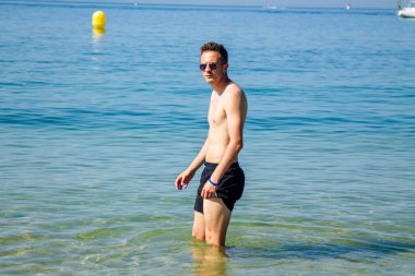 Kumsalda yıkanan yakışıklı genç adam.