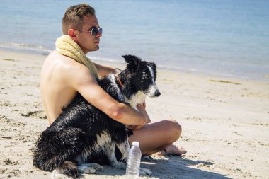 Plajda köpeğiyle genç bir adamın portresi.