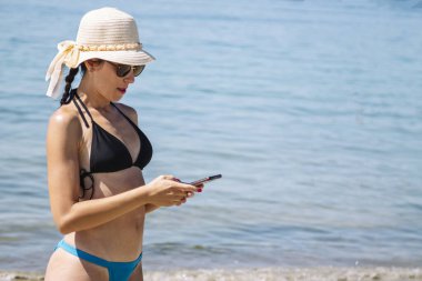 Sahilde cep telefonuyla konuşan bir kadın.