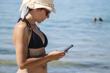 Sahilde cep telefonuyla konuşan bir kadın.